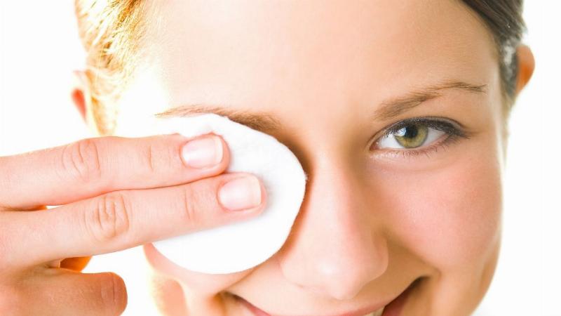 Một người đang nhẹ nhàng rửa sạch vùng mí mắt bằng sản phẩm vệ sinh mắt chuyên dụng, thể hiện quy trình chăm sóc mắt hàng ngày.