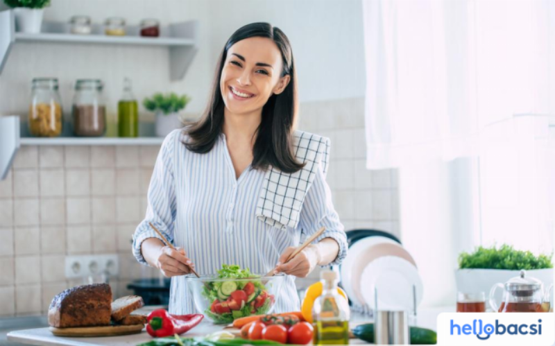 Một người đang ốm, ngồi tựa lưng trên giường và uống một cốc nước lọc hoặc nước điện giải, thể hiện việc bù nước khi sốt.