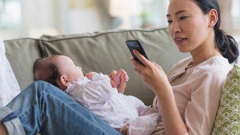 Một em bé đang ngồi chơi game trên điện thoại, thiết bị phát ra sóng điện từ, có thể ảnh hưởng đến não trẻ.