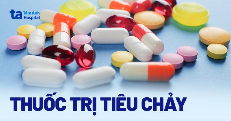 Hình ảnh một bàn tay đang cầm vài viên nang hoặc viên nén Trinh Nữ Hoàng Cung, trên nền mờ là bao bì sản phẩm, thể hiện dạng bào chế hiện đại.